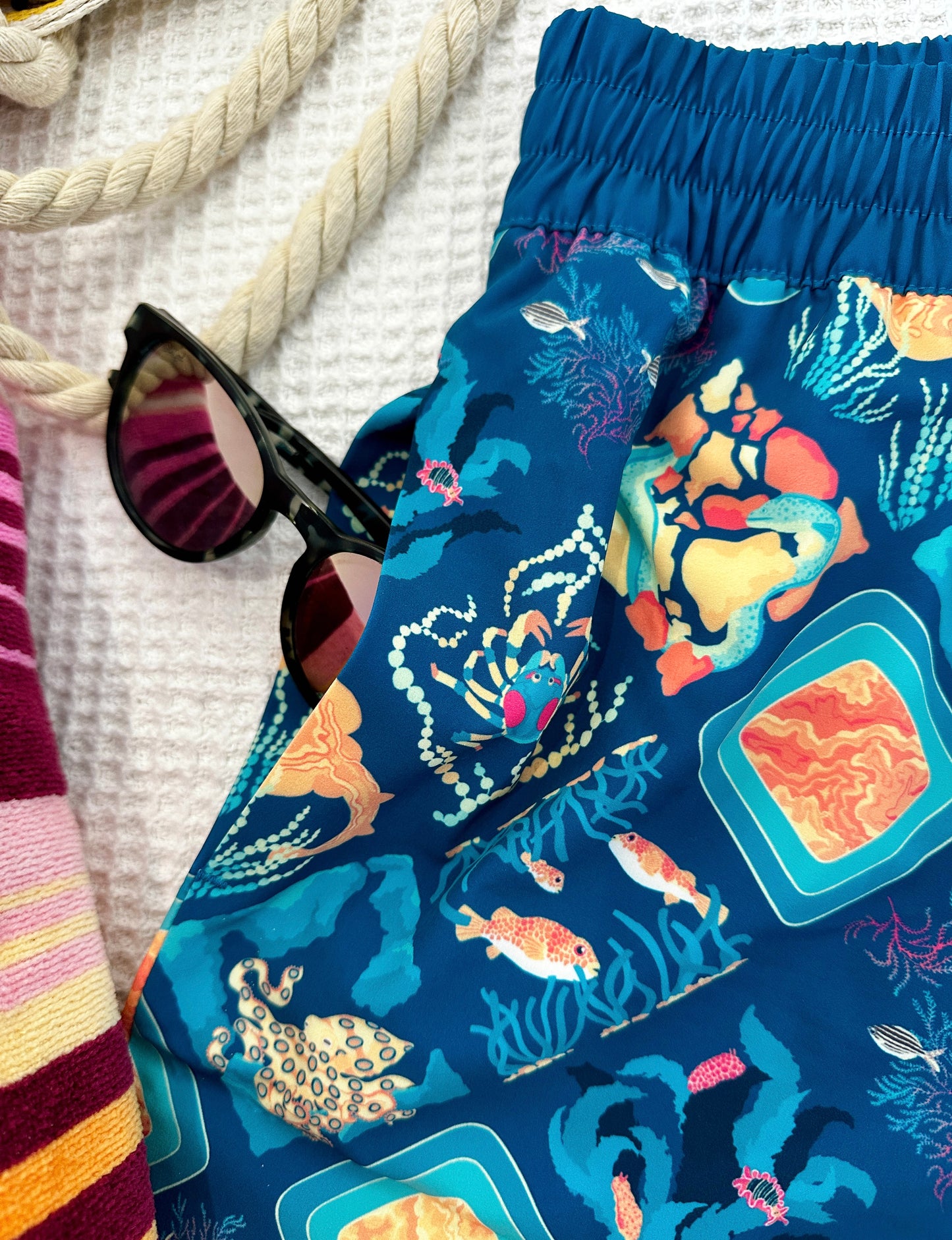 Aqua Blue shorts with ocean-themed pattern on a white background