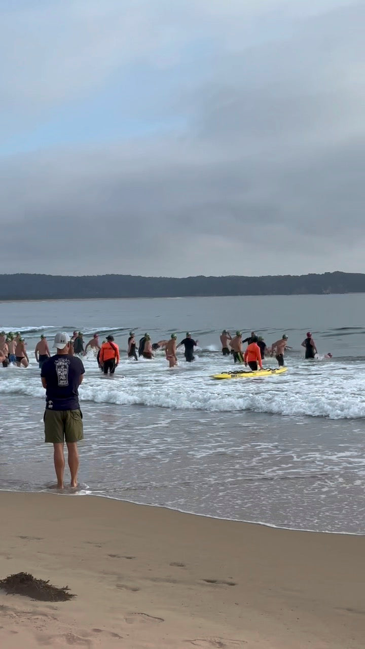 People on a beach running into ocean ready to race