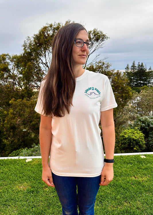 Person wearing a white t-shirt with a logo outdoors