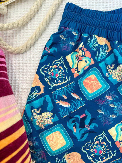 Aqua blue shorts with ocean-themed pattern on a textured surface