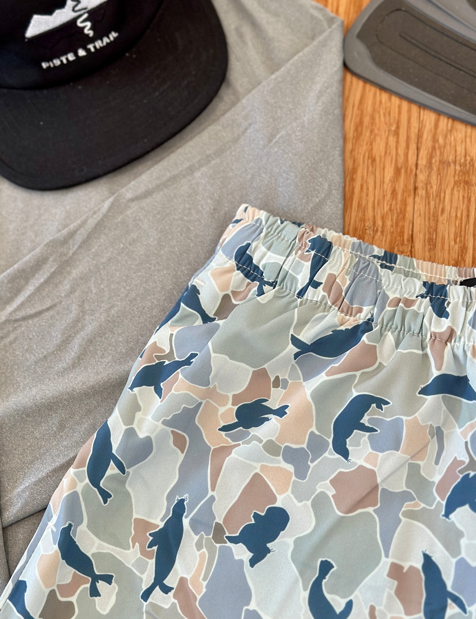 Patterned board shorts with Seal shapes on a wooden surface