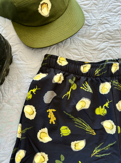 Dark Navy shorts with green seaweeds, and oysters pattern on a white textured surface with a green oyster cap.