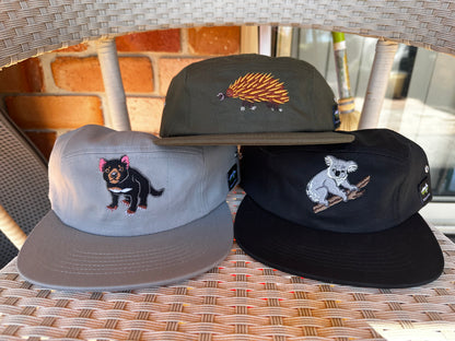 Three embroidered caps on a wicker surface with blurred background