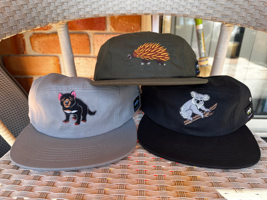 Three embroidered caps on a wicker surface with blurred background