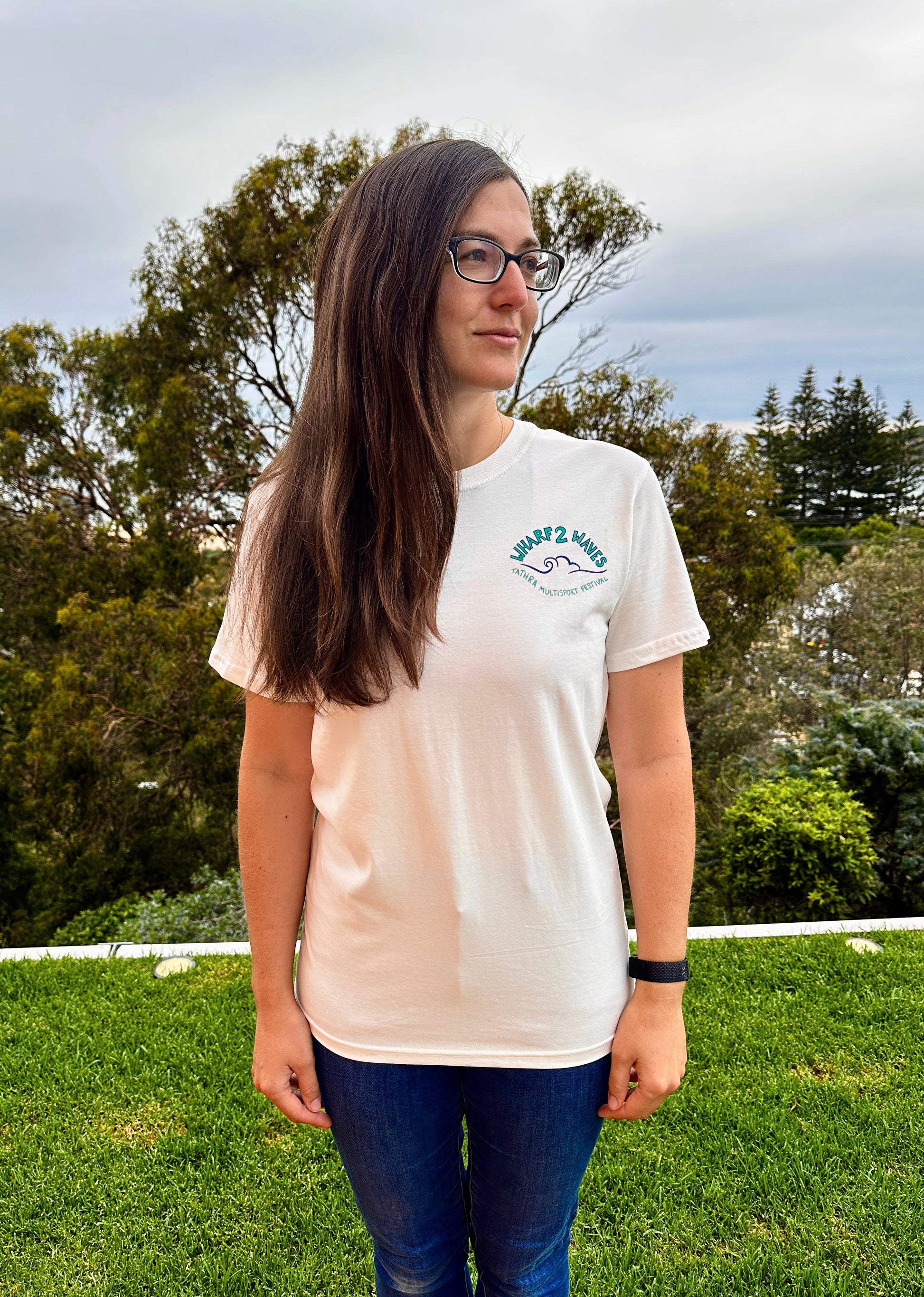 Person wearing a white t-shirt with a logo outdoors