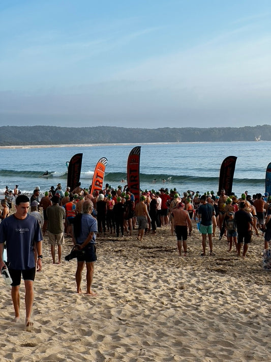 People ready to race (swimming) on a beach banners, under a clear sky.