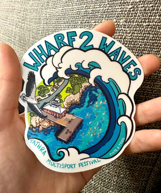 Sticker with 'Wharf 2 Waves' design held in a hand against a textured background