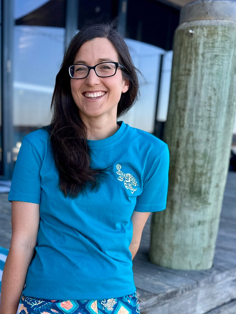 Woman wearing a blue t-shirt with an embroidered octopus, standing outdoors.