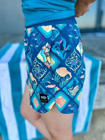 Colorful patterned shorts worn by a person on a striped chair.