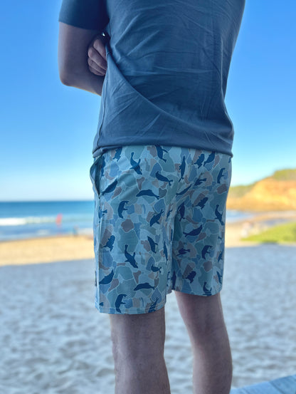 Person wearing blue shorts with a seal pattern at a beach.