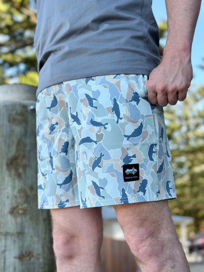 Person wearing blue camouflage shorts with a brand logo, standing outdoors.